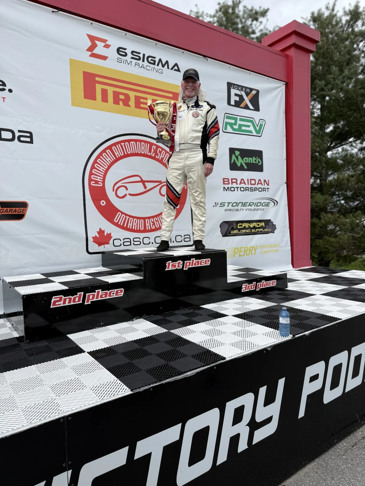 A driver holding a trophy on a victory podium