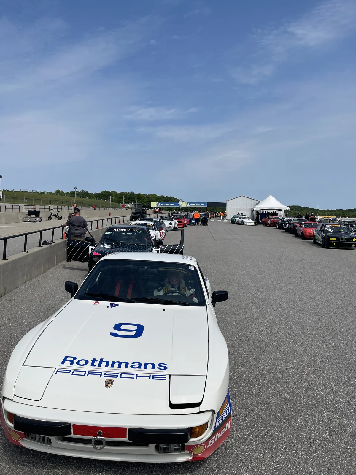 The white number 9 Porsche at the front of a paddock queue